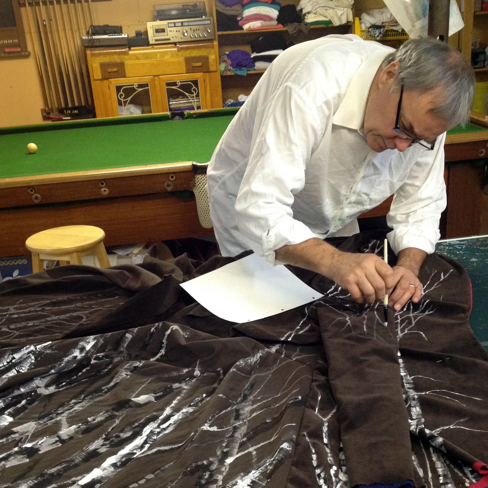 Man painting on fabric- birch trees.